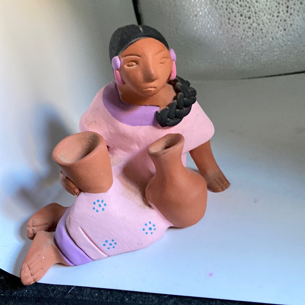 American Indian made of red clay holding 2 pots